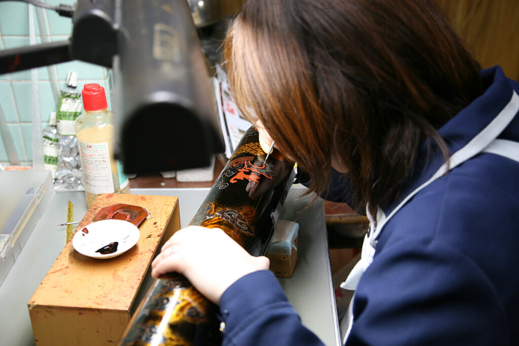 金沢仏壇の丸柱に蒔絵を描く様子。